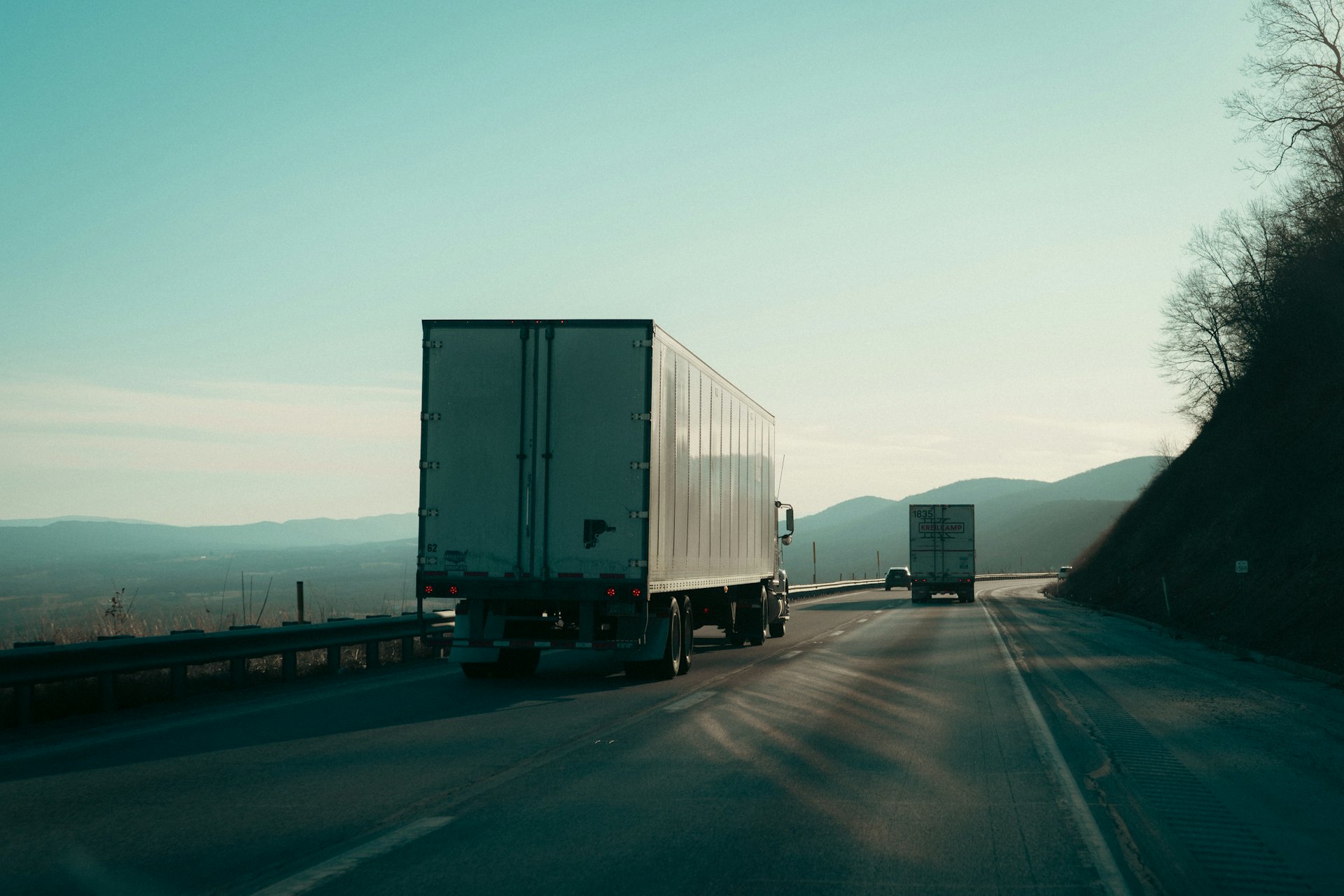 A tractor-trailer on an open highway at dusk